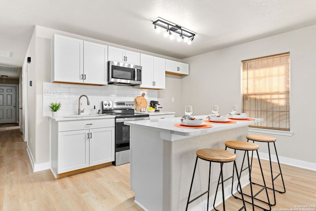 kitchen with appliances with stainless steel finishes, a center island, white cabinetry, and a breakfast bar area