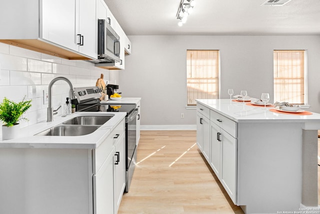 kitchen featuring sink, a center island, white cabinets, and appliances with stainless steel finishes