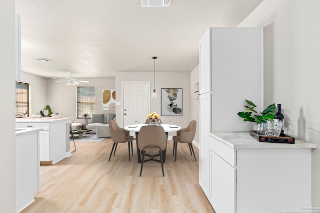 dining area with light wood-type flooring and ceiling fan