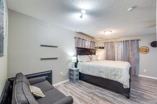 150 S Fisher Ln, Poteet, TX 78065 - bedroom with baseboards, wood finished floors, and a textured ceiling