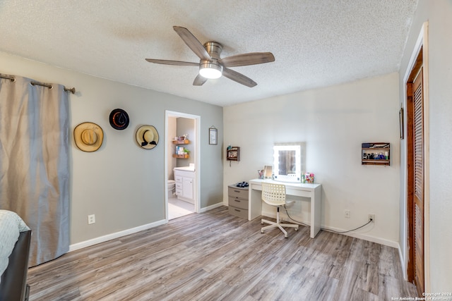 office area featuring built in desk, light hardwood / wood-style floors, a textured ceiling, and ceiling fan