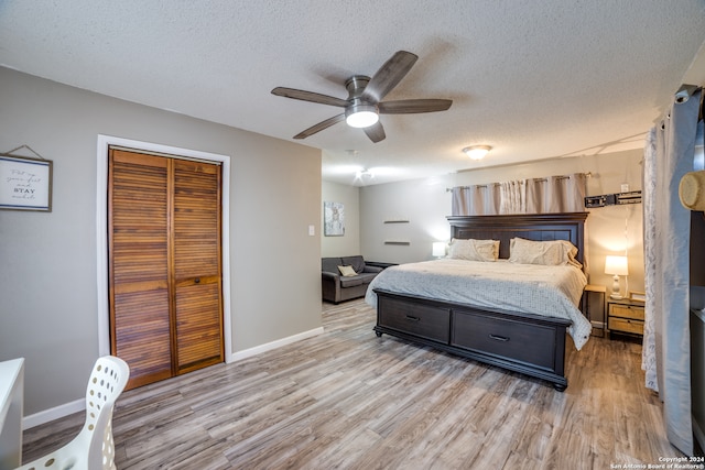 bedroom with a closet, ceiling fan, a textured ceiling, and light hardwood / wood-style floors