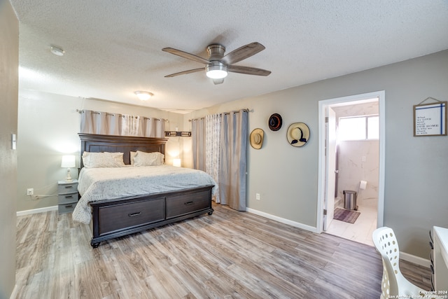 bedroom featuring light hardwood / wood-style flooring, ceiling fan, a textured ceiling, and ensuite bath