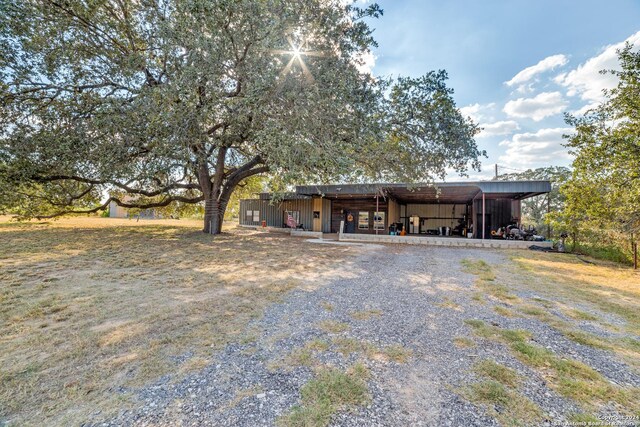 150 S Fisher Ln, Poteet, TX 78065 - view of front of house featuring a detached carport, gravel driveway, an outbuilding, and an outdoor structure