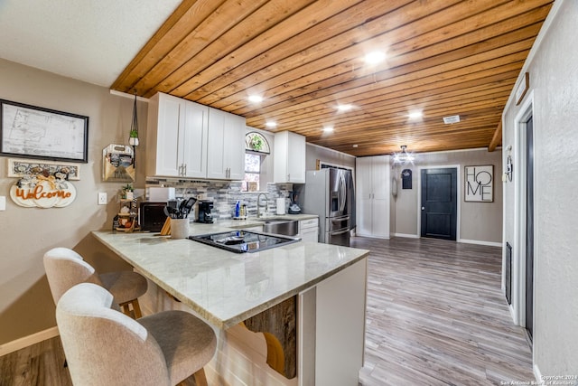 150 S Fisher Ln, Poteet, TX 78065 - kitchen featuring a breakfast bar, stainless steel fridge with ice dispenser, baseboards, white cabinets, and a peninsula