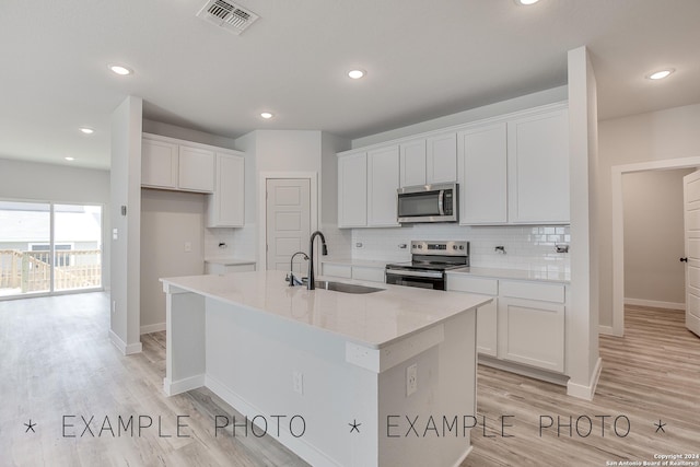 kitchen with a center island with sink, white cabinets, stainless steel appliances, and sink