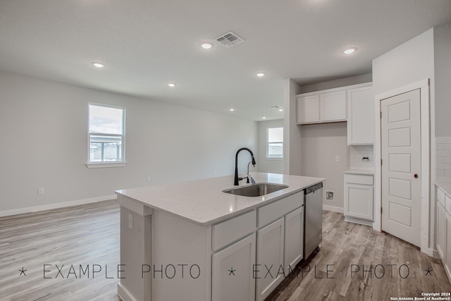 kitchen featuring tasteful backsplash, light stone counters, sink, a center island with sink, and dishwasher