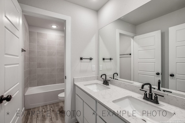 full bathroom with toilet, vanity, wood-type flooring, and tiled shower / bath