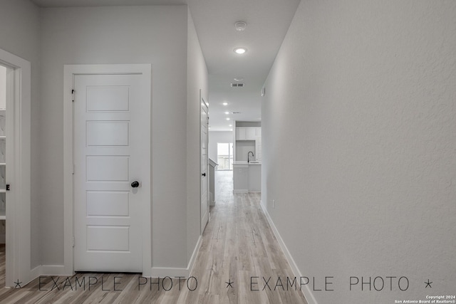 corridor with sink and light hardwood / wood-style flooring