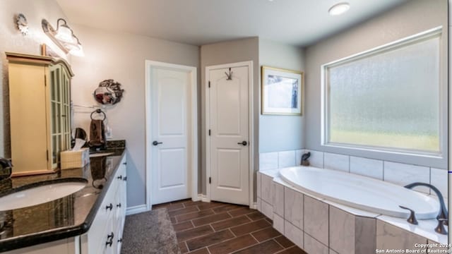 bathroom featuring vanity, hardwood / wood-style floors, and tiled bath