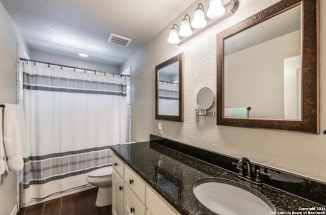 bathroom featuring toilet, hardwood / wood-style floors, curtained shower, vanity, and a textured ceiling