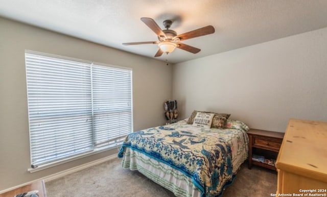 bedroom featuring ceiling fan, multiple windows, and dark carpet