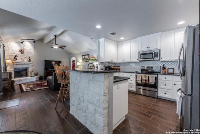 kitchen featuring a kitchen bar, white cabinetry, ceiling fan, stainless steel appliances, and dark wood-type flooring