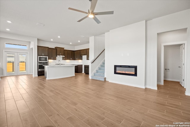 unfurnished living room featuring sink, french doors, light hardwood / wood-style floors, and ceiling fan