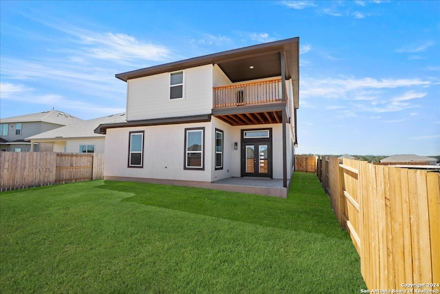 back of property with a balcony, a patio, and a lawn