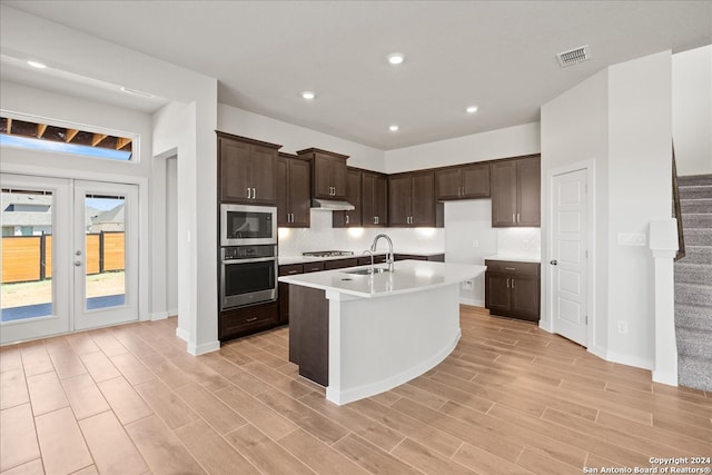 kitchen featuring light hardwood / wood-style flooring, stainless steel appliances, sink, and an island with sink