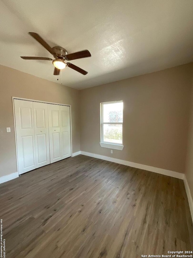 unfurnished bedroom with a closet, dark hardwood / wood-style floors, a textured ceiling, and ceiling fan