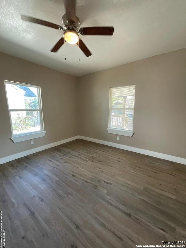 empty room with ceiling fan and dark hardwood / wood-style flooring