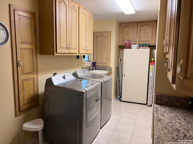 laundry room featuring cabinets, light tile patterned flooring, sink, and washing machine and clothes dryer