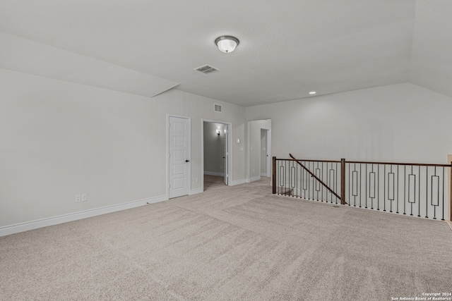 carpeted empty room with lofted ceiling