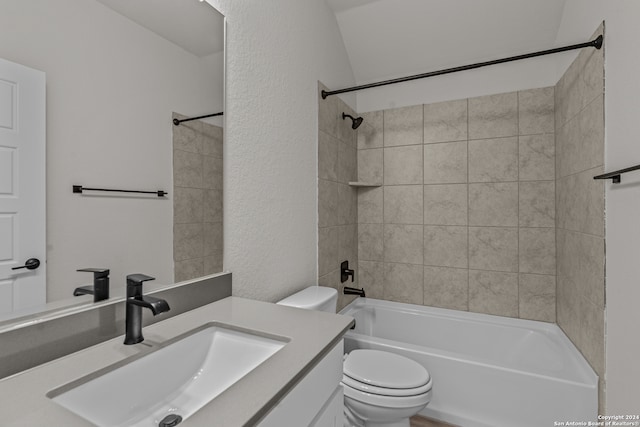 full bathroom with tiled shower / bath, vanity, lofted ceiling, and toilet