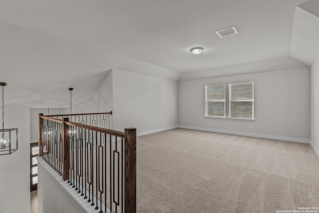 additional living space with a textured ceiling, lofted ceiling, a chandelier, and light colored carpet