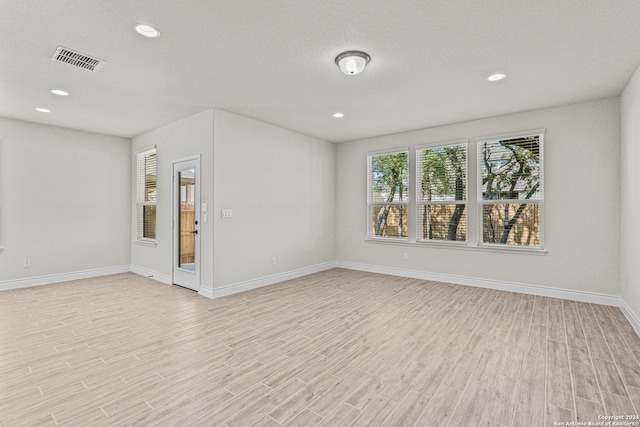 unfurnished room with a textured ceiling and light hardwood / wood-style floors