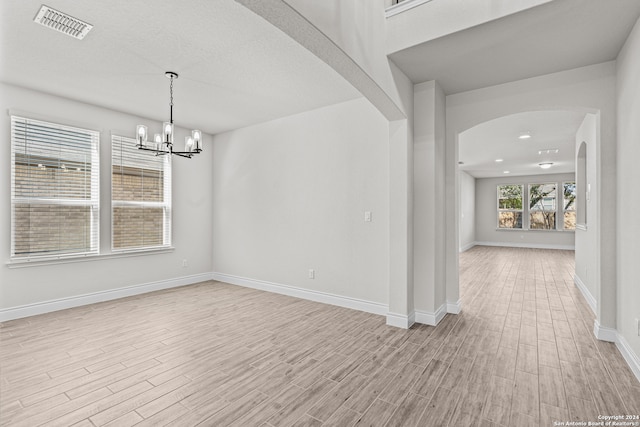 spare room with a chandelier and light hardwood / wood-style flooring