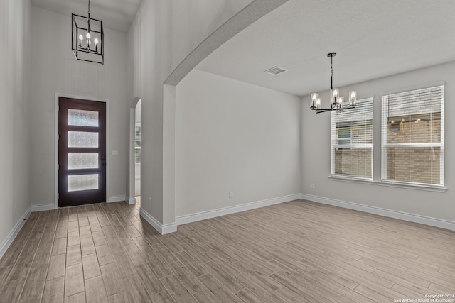 foyer with a wealth of natural light, light wood-type flooring, and an inviting chandelier