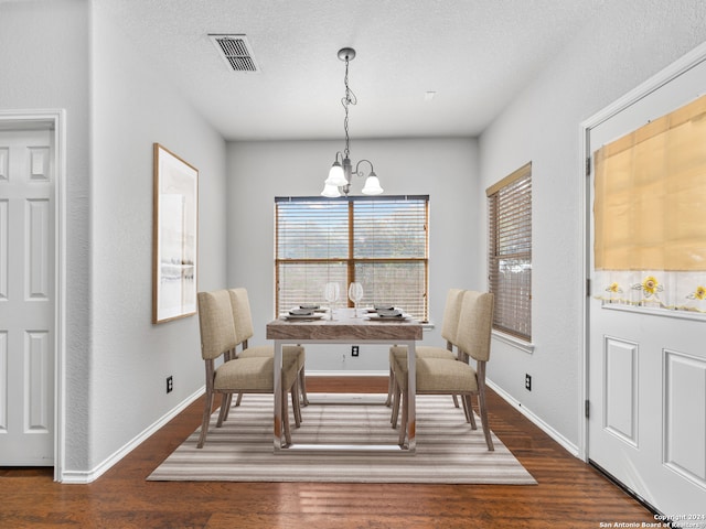 dining space featuring a textured ceiling, a notable chandelier, and dark hardwood / wood-style floors