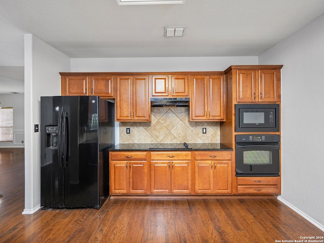 kitchen featuring black appliances, dark wood-type flooring, tasteful backsplash, and dark stone counters