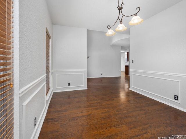 unfurnished dining area with an inviting chandelier and dark hardwood / wood-style flooring