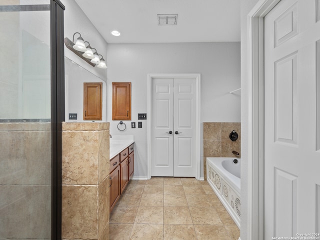 bathroom with vanity, a relaxing tiled tub, and tile patterned floors