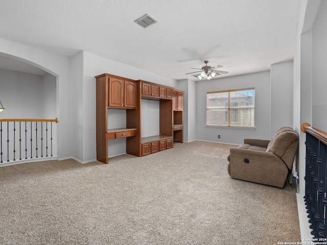 carpeted living room with ceiling fan and a textured ceiling