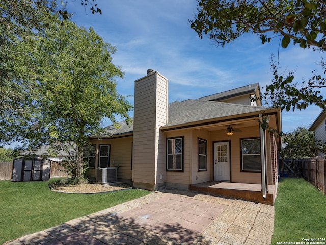 view of front facade featuring ceiling fan, a storage shed, a patio area, a front lawn, and central AC