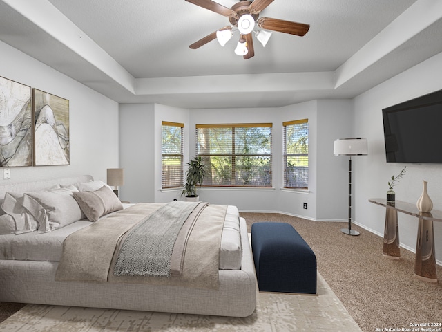 carpeted bedroom with a tray ceiling and ceiling fan