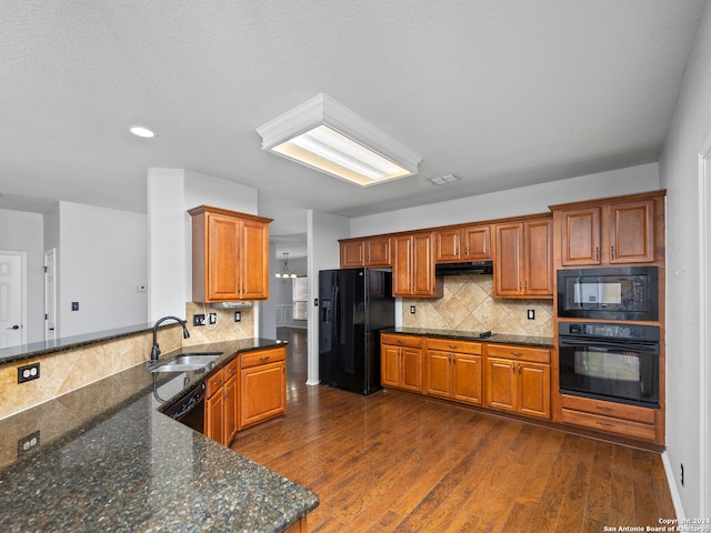 kitchen with dark stone countertops, sink, black appliances, dark hardwood / wood-style flooring, and tasteful backsplash