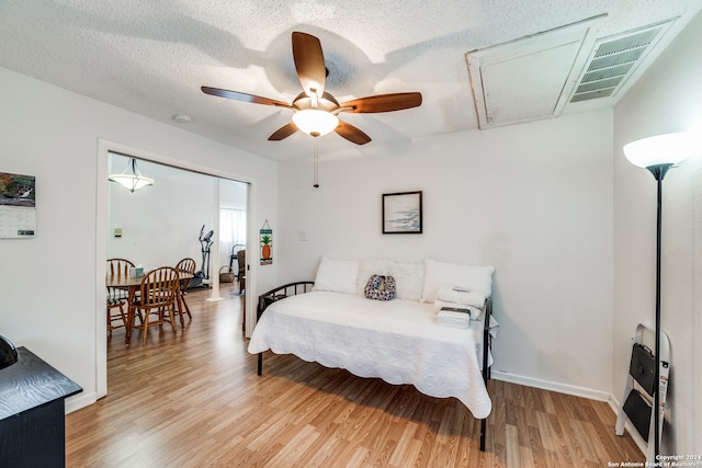 bedroom featuring light hardwood / wood-style flooring, a textured ceiling, heating unit, and ceiling fan