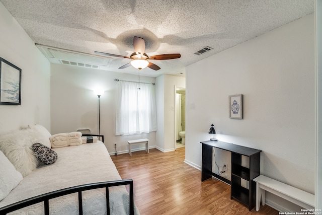 bedroom with hardwood / wood-style floors, a textured ceiling, connected bathroom, and ceiling fan