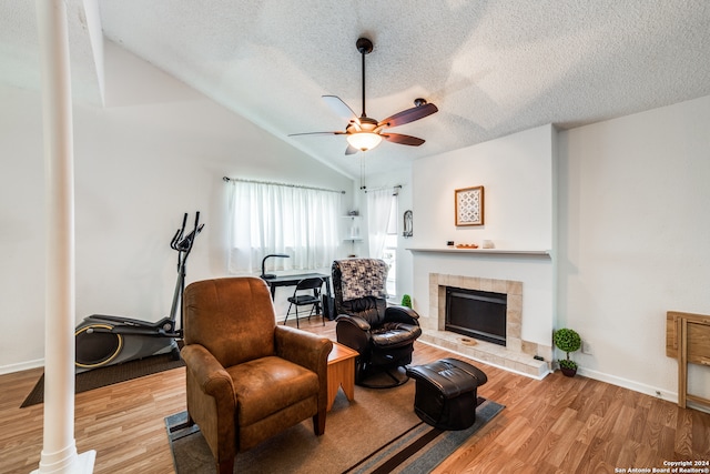 living room with vaulted ceiling, light hardwood / wood-style flooring, a fireplace, and ceiling fan