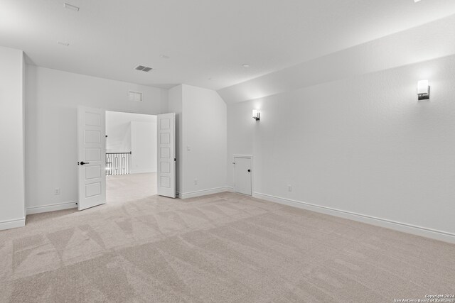 carpeted empty room with lofted ceiling