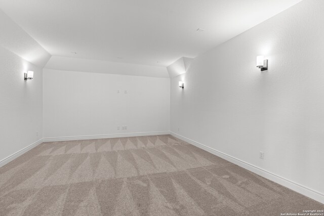 carpeted empty room with vaulted ceiling