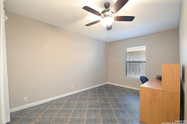 unfurnished office with ceiling fan, a textured ceiling, and dark tile patterned floors