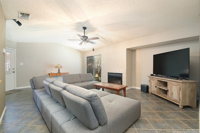 tiled living room featuring a textured ceiling, a tile fireplace, and ceiling fan