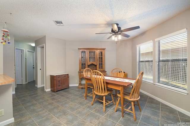 tiled dining area featuring ceiling fan and a textured ceiling