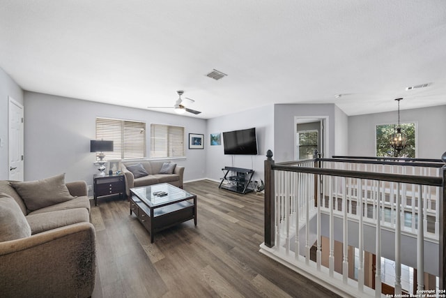 living room with ceiling fan with notable chandelier and dark hardwood / wood-style floors