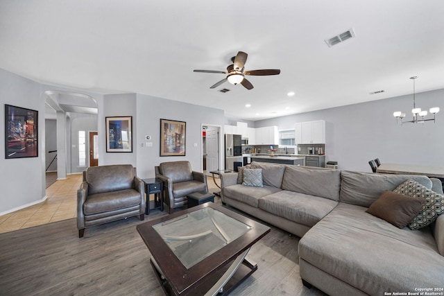 living room featuring a wealth of natural light, light wood-type flooring, and ceiling fan with notable chandelier