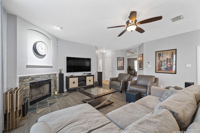 living room featuring hardwood / wood-style floors, a stone fireplace, and ceiling fan