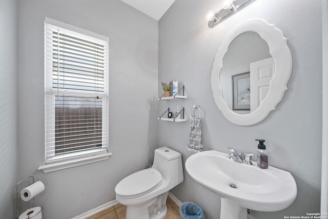 bathroom with toilet, sink, and tile patterned flooring