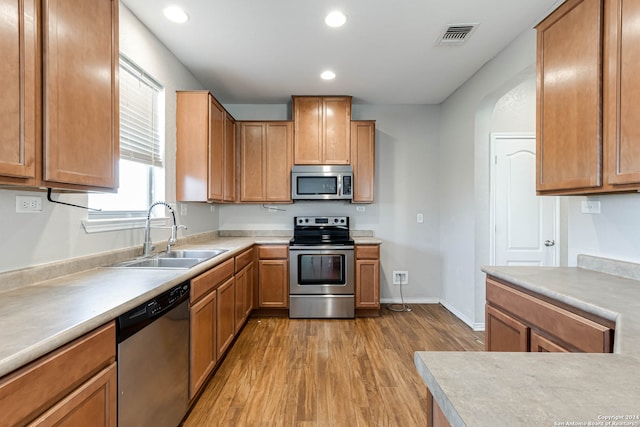 kitchen featuring appliances with stainless steel finishes, sink, and light wood-type flooring